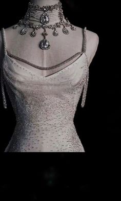 the back of a white dress with silver beads on it