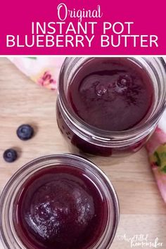 two jars filled with blueberry butter on top of a wooden table