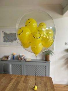 some yellow balloons with smiley faces on them sitting in front of a wooden counter top