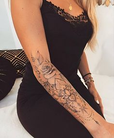 a woman with a tattoo on her arm and leg is sitting in a black dress