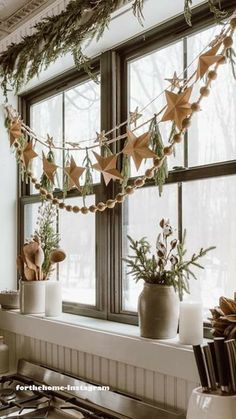 a kitchen window sill filled with potted plants and star garland hanging from the windowsill