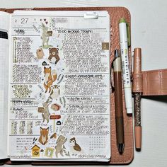 an open planner with animals on it next to a pen and two pens in front of it