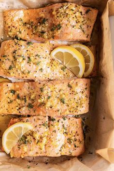 salmon with lemons and herbs in a baking dish on parchment paper, ready to be cooked