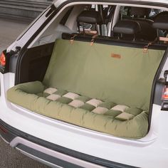 the back end of a white car with an open trunk and seat cushion on it