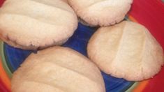 four sugar cookies are on a plate with blue and orange trim around them, ready to be eaten