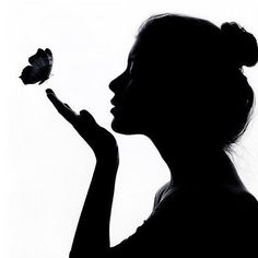 the silhouette of a woman holding a butterfly in one hand and a flower in the other