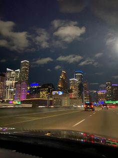 the city skyline is lit up at night with bright lights in the foreground and clouds in the background