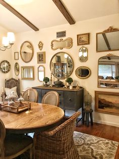 a dining room table with chairs and mirrors on the wall above it, along with other antique furniture