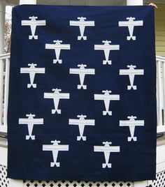 a black and white quilt with airplanes on it in front of a porch railing area