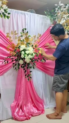 a man standing next to a pink and white floral arrangement