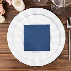 a white plate with a blue napkin sits on a wooden table next to silverware