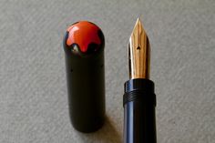 a black pen with a red and black design on it next to a pencil holder