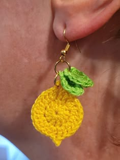 a woman wearing yellow and green crochet earrings with a flower on the end