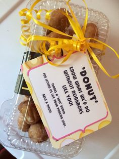 a clear bowl filled with donuts and a yellow ribbon tied around the tag that says donut shop