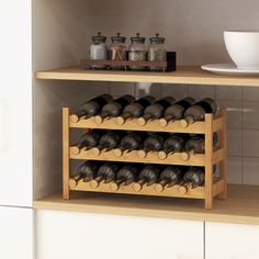 a wine rack filled with bottles and glasses on top of a wooden shelf next to a white bowl