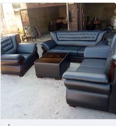 a group of black leather couches and chairs in a room with concrete flooring