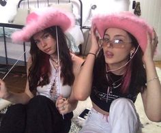 two women wearing pink hats sitting on a bed