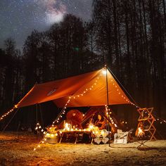 a large tent with lights on it in the middle of a forest under a night sky filled with stars