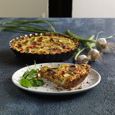 a quiche on a plate next to another dish