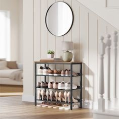 there is a shoe rack with many pairs of shoes on it and a round mirror