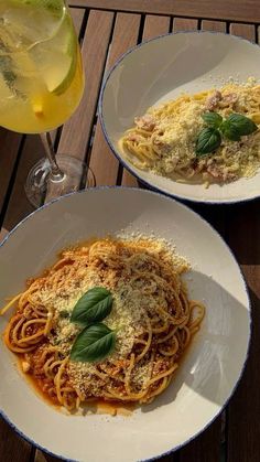 two plates of spaghetti with basil on top