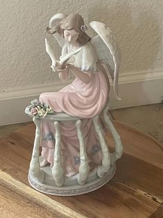 an angel figurine sitting on top of a wooden table next to a wall