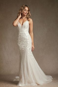 a woman in a wedding dress posing for the camera with her hand on her head