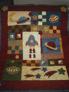 a quilted wall hanging with space themed items on it's sides and in the center