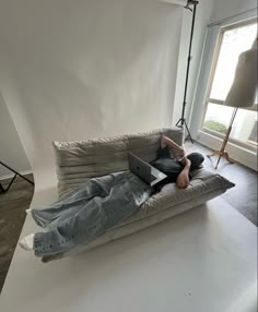 a person laying on a couch with a laptop