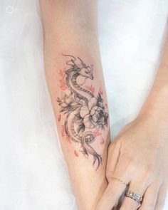 a woman's arm with a dragon tattoo on the left side of her arm