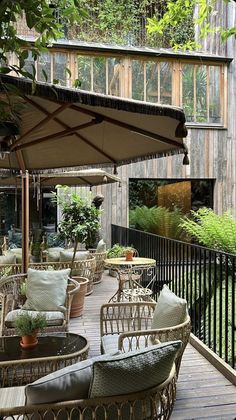 an outdoor patio with wicker furniture and umbrellas on the deck, surrounded by greenery