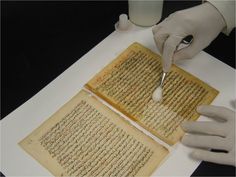 a person in white gloves writing on an old book