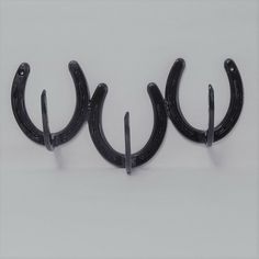 three black metal hooks on a white wall