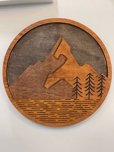 a wooden clock with mountains and trees on it