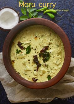 a wooden bowl filled with soup next to a spoon and some green leafy leaves