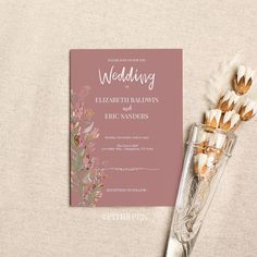 the wedding card is next to some dried flowers