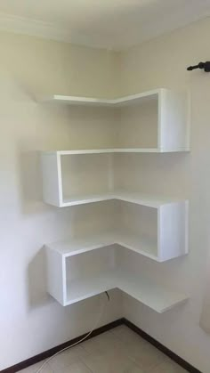 an empty room with white shelves in the corner and tile flooring on the ground