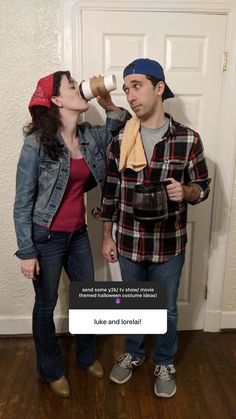 two people standing next to each other in front of a door drinking out of cups