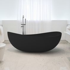 a large black bath tub sitting next to a toilet in a white bathroom with curtains