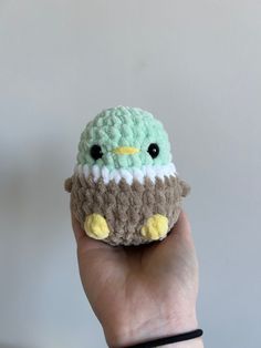 a hand holding a small crocheted bird