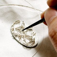 a person is working on a silver object with a small needle in it's center