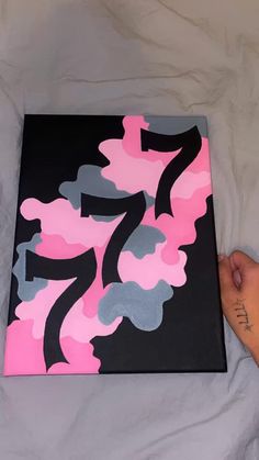 a person is holding up a pink and black painting