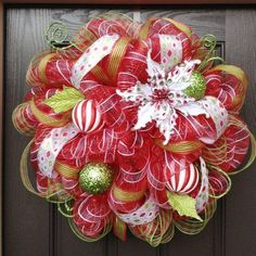 a red and green christmas wreath hanging on a door