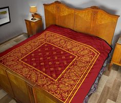 a bed with a red and gold bedspread on it