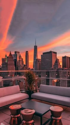 an outdoor patio with couches and tables overlooking the cityscape at sunset or dawn