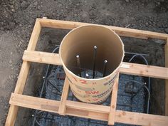 a bucket filled with lots of tools sitting on top of a wooden frame in the dirt