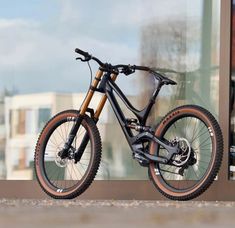 a mountain bike parked in front of a window with the reflection of buildings behind it