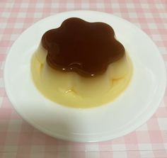 a small white plate topped with jelly and sauce on top of a pink checkered table cloth