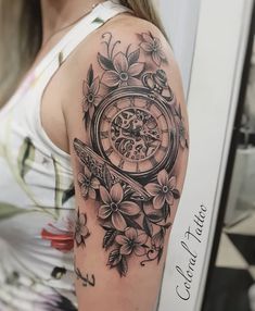 a woman's arm with a clock and flowers tattoo on her left upper arm