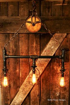 an old fashioned light fixture hanging from the side of a wooden wall with three bulbs on it